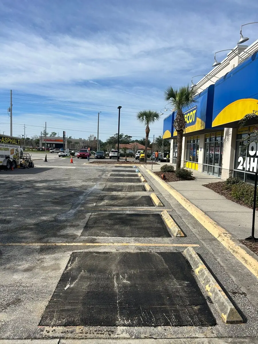Multiple asphalt patches across a series of parking stalls in a commercial lot