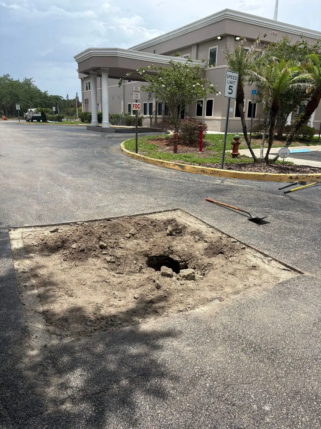 Sinkhole from compromised base under a Central Florida parking lot showing the underlying soil and grate exposed