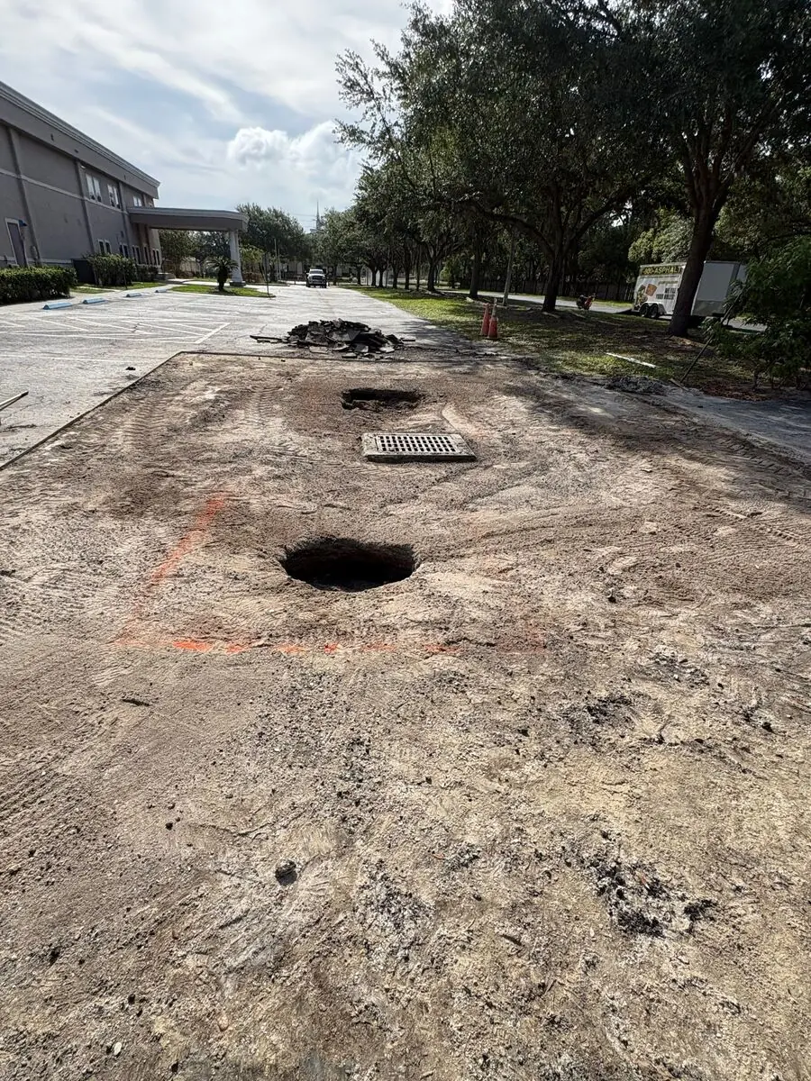 Sinkhole in an asphalt parking lot showing the compromised base underneath a catch basin