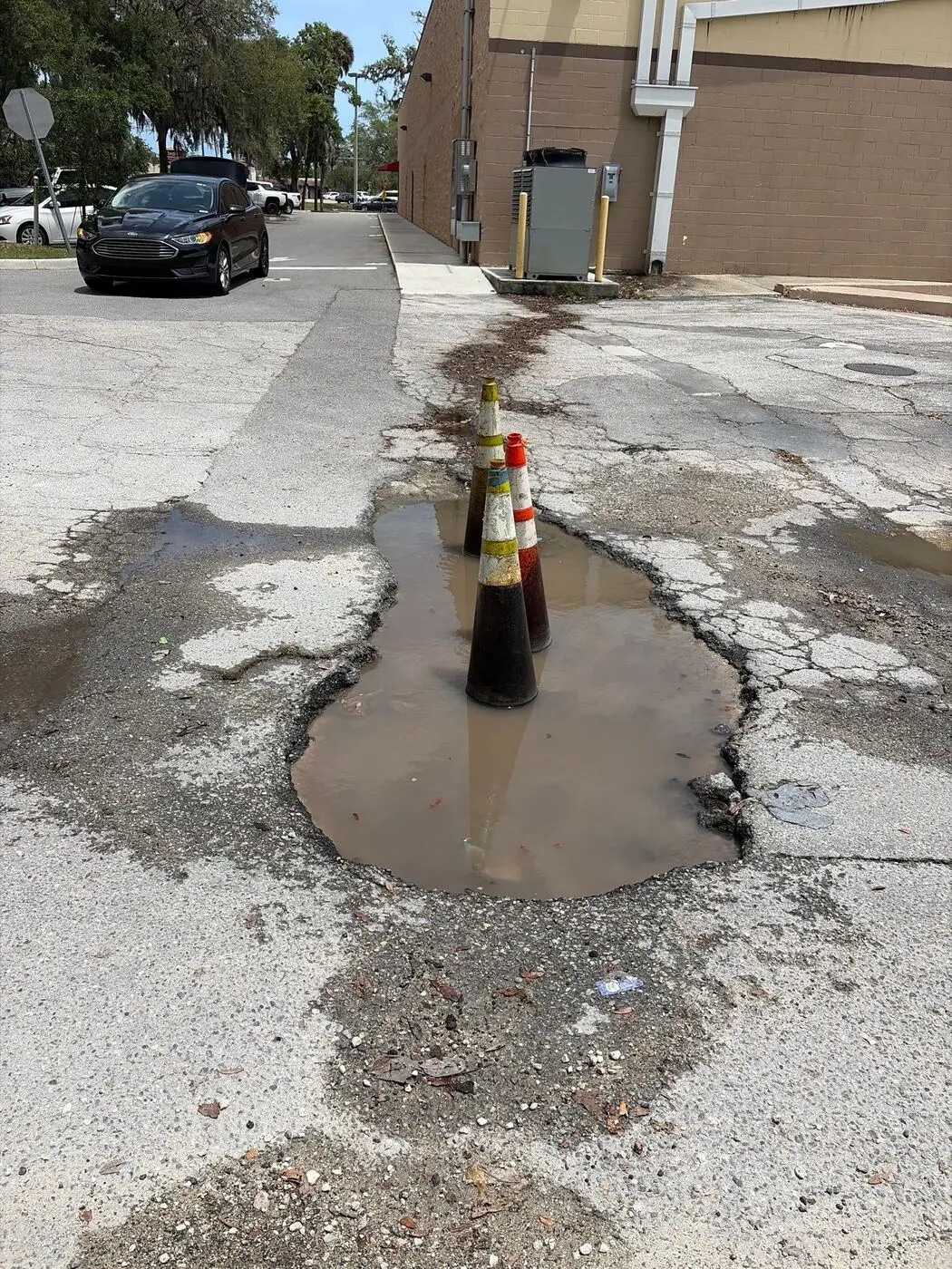Standing water pooling in a damaged asphalt parking lot in Central Florida