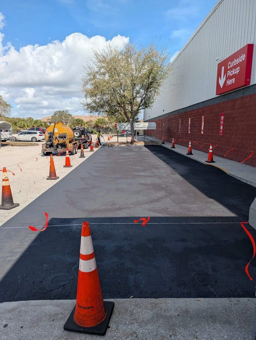 Crew coning off a section of parking lot before sealcoating begins