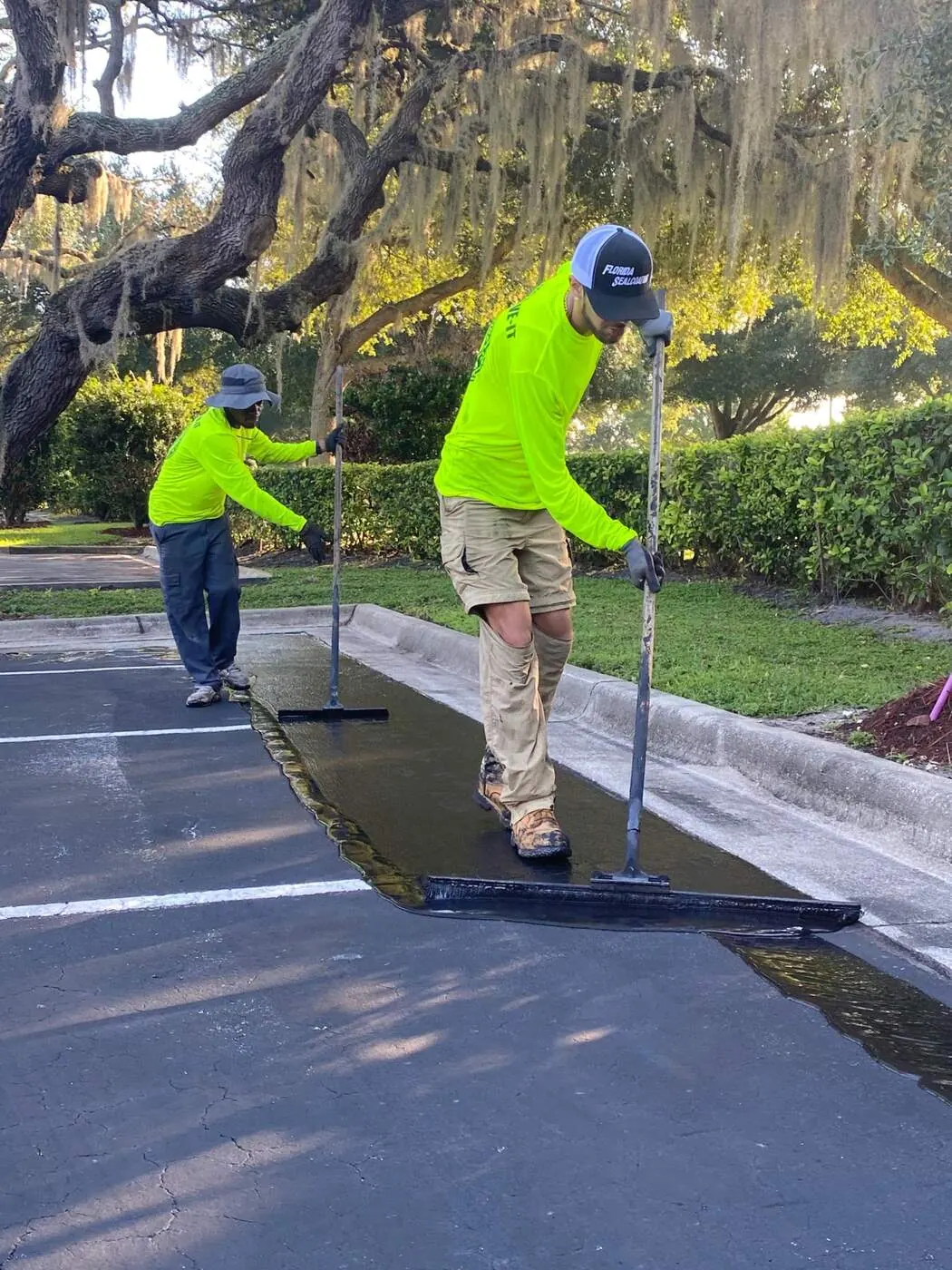 Sealcoat cut-in with brushes along parking lot curb edge