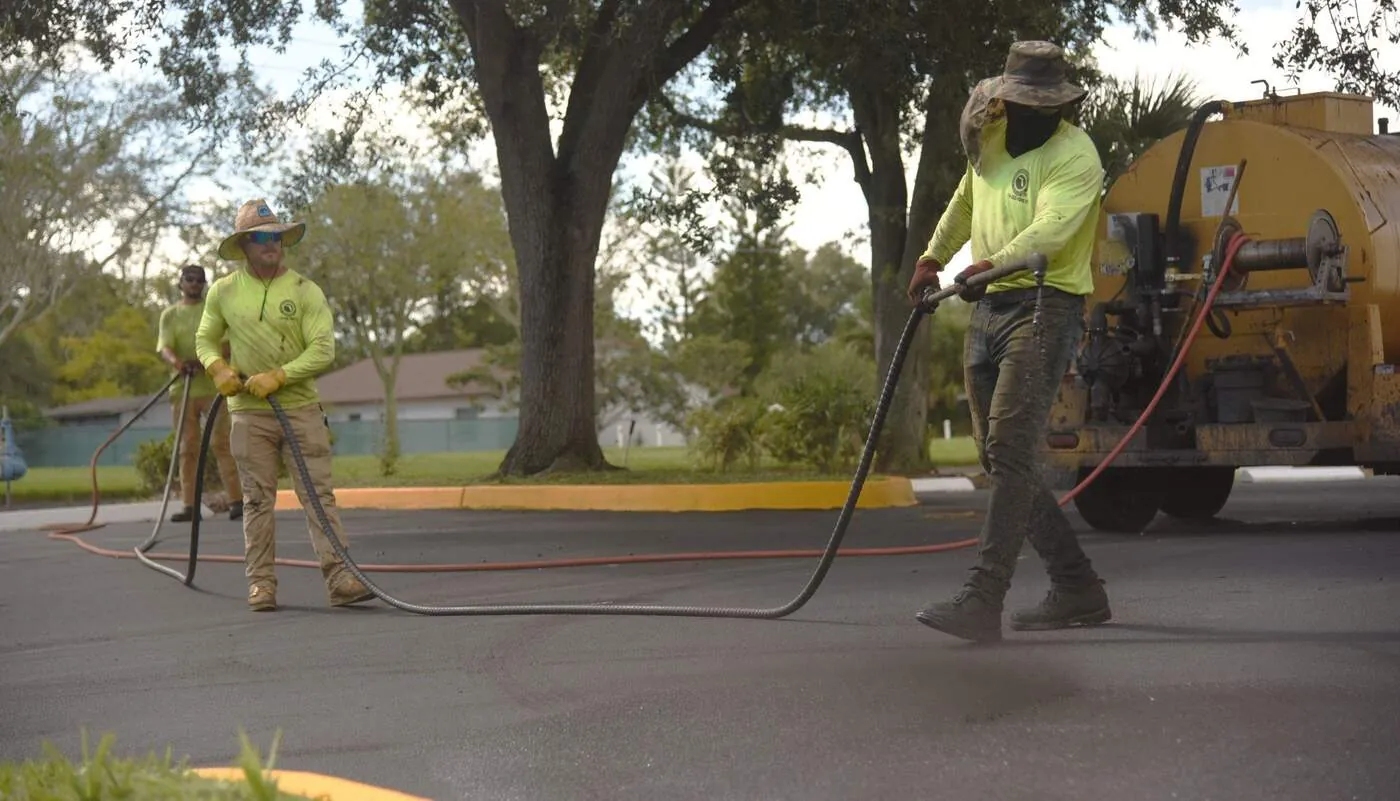 Florida Sealcoating crew spraying sealcoat on a commercial parking lot in Central Florida
